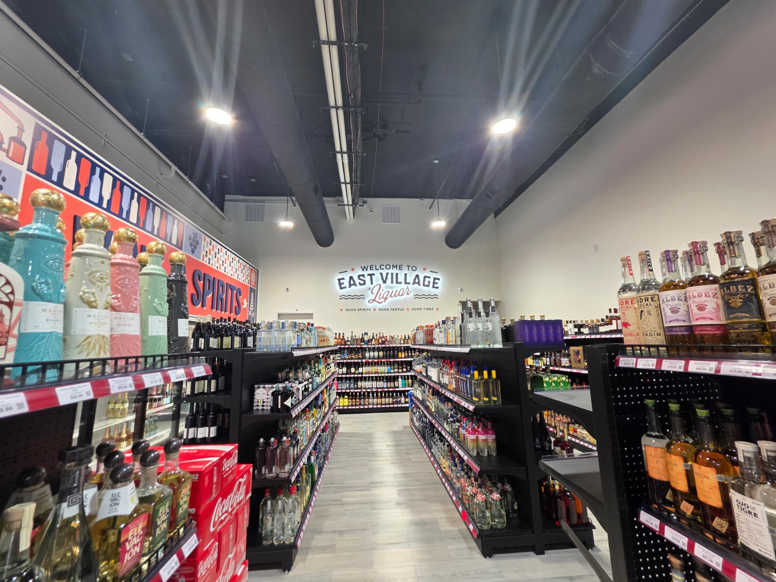 Spirits aisles leading to the Welcome to East Village Liquor mural
