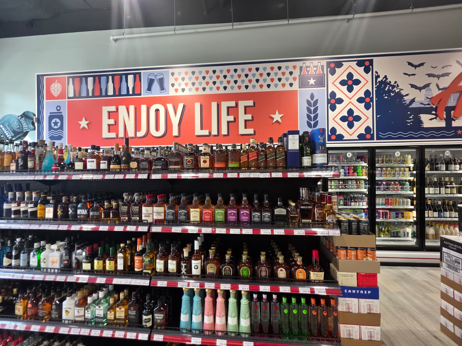Top shelf whiskey selection under the Enjoy Life mural